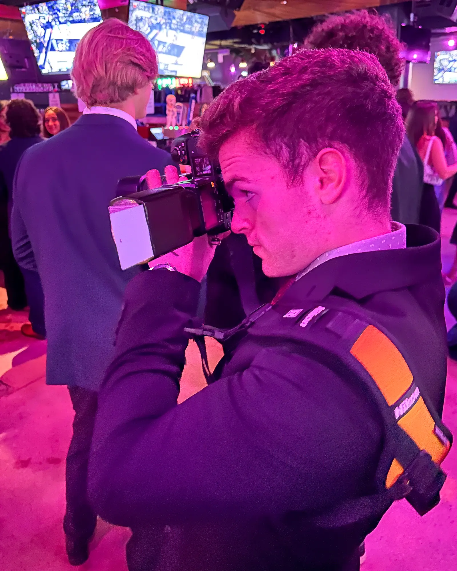 Kyle Soule photographing a formal event under magenta venue lighting.