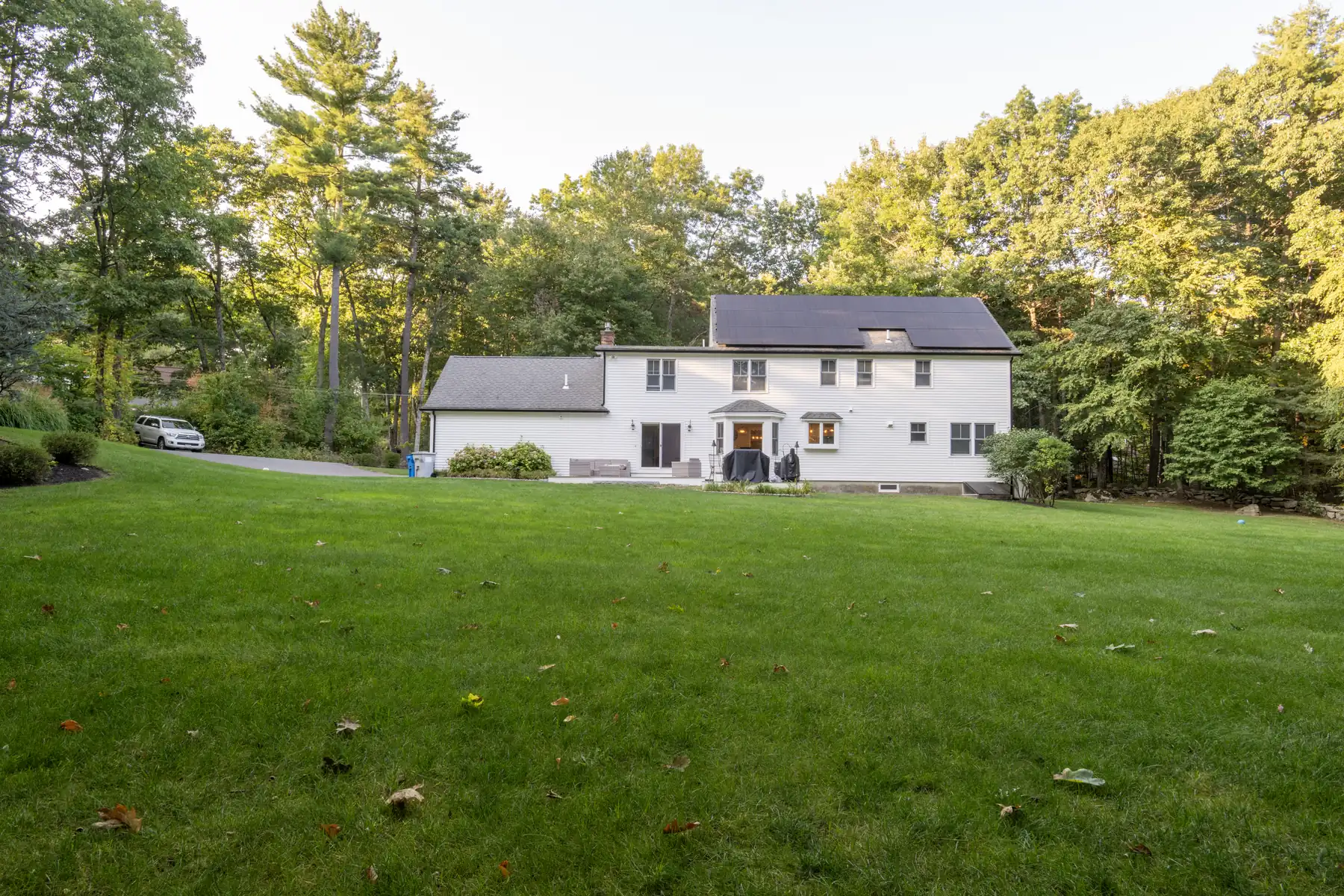 Rear exterior of a white two-story home opening onto a broad lawn.
