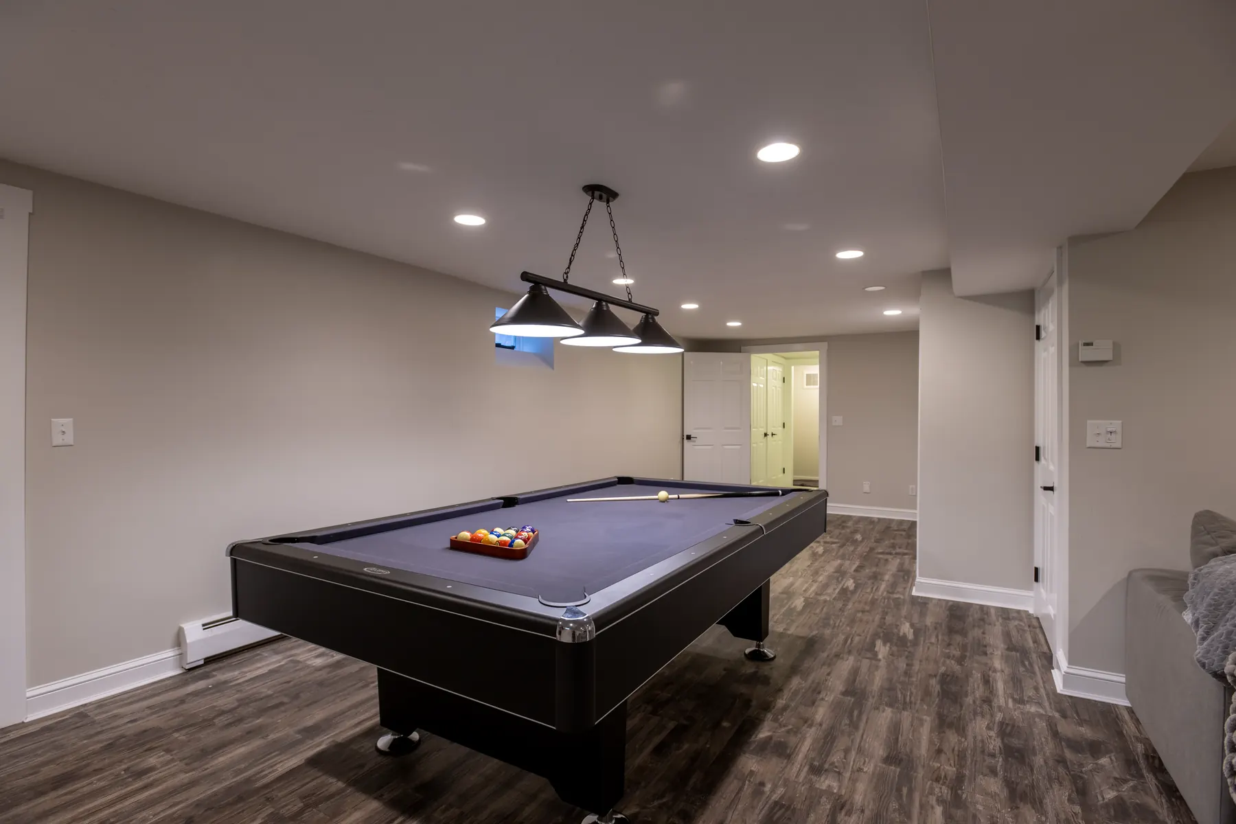 Finished basement game room with a pool table and wood-look flooring.