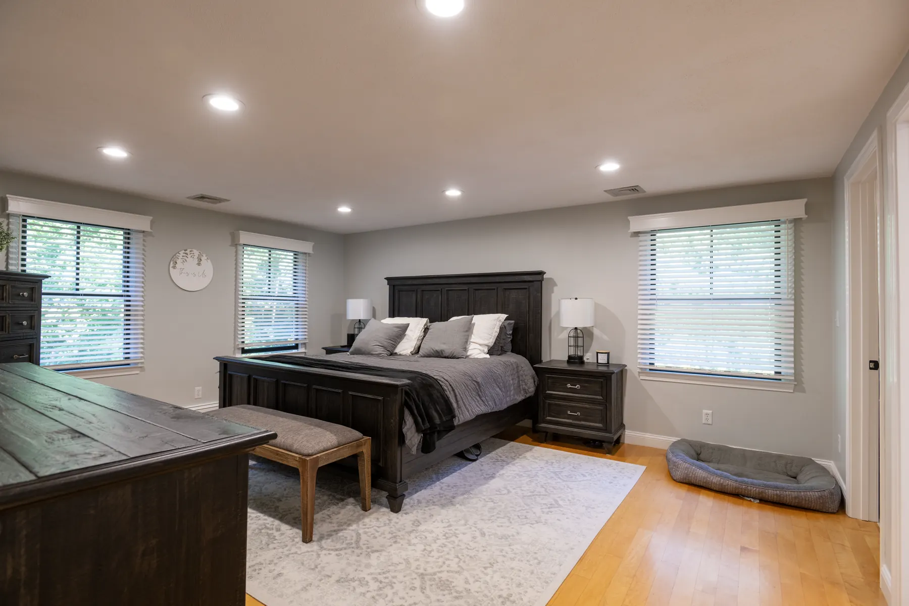 Primary bedroom with dark wood furniture and windows along two walls.