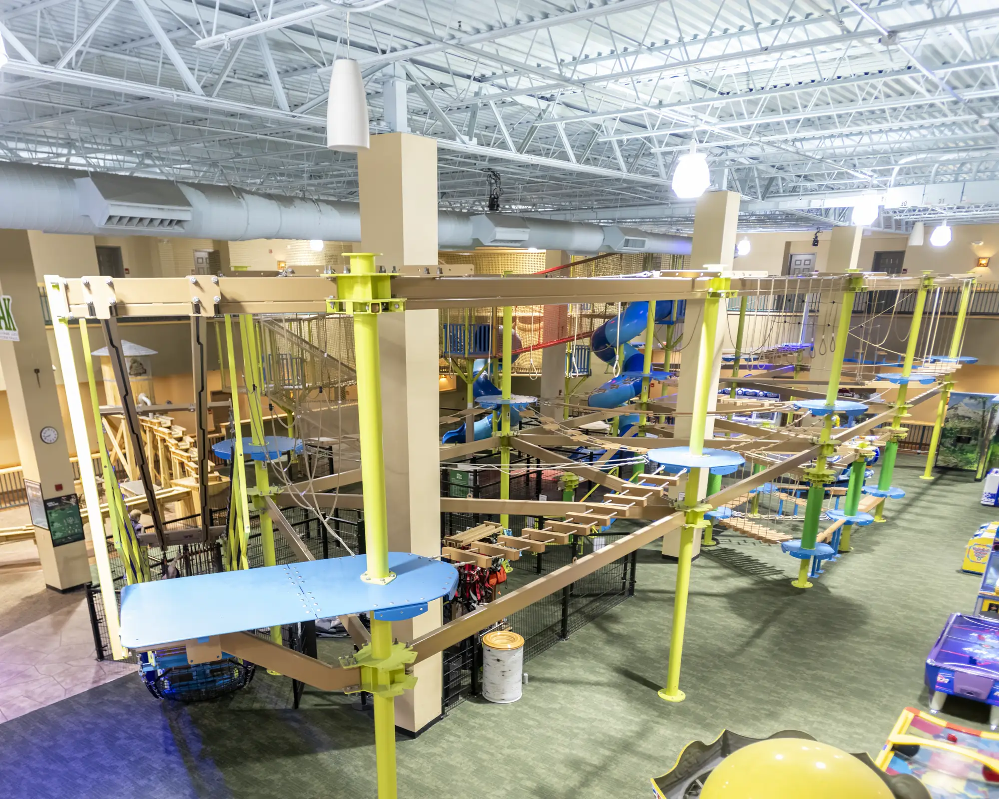 Elevated view across the indoor ropes course and its suspended walking obstacles.