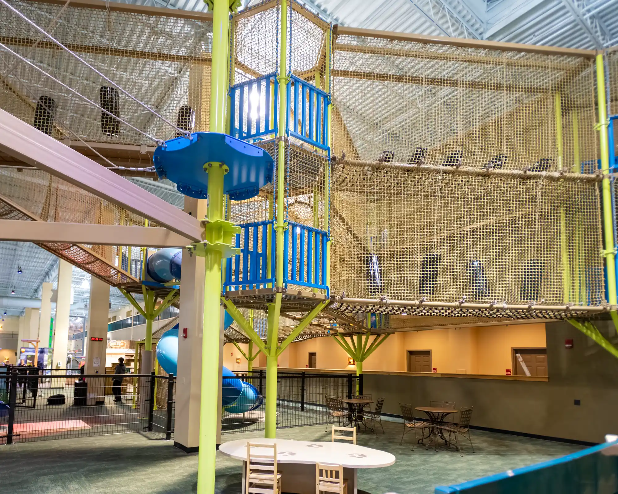 Netted platform tower and elevated walkways seen from the adventure park floor.