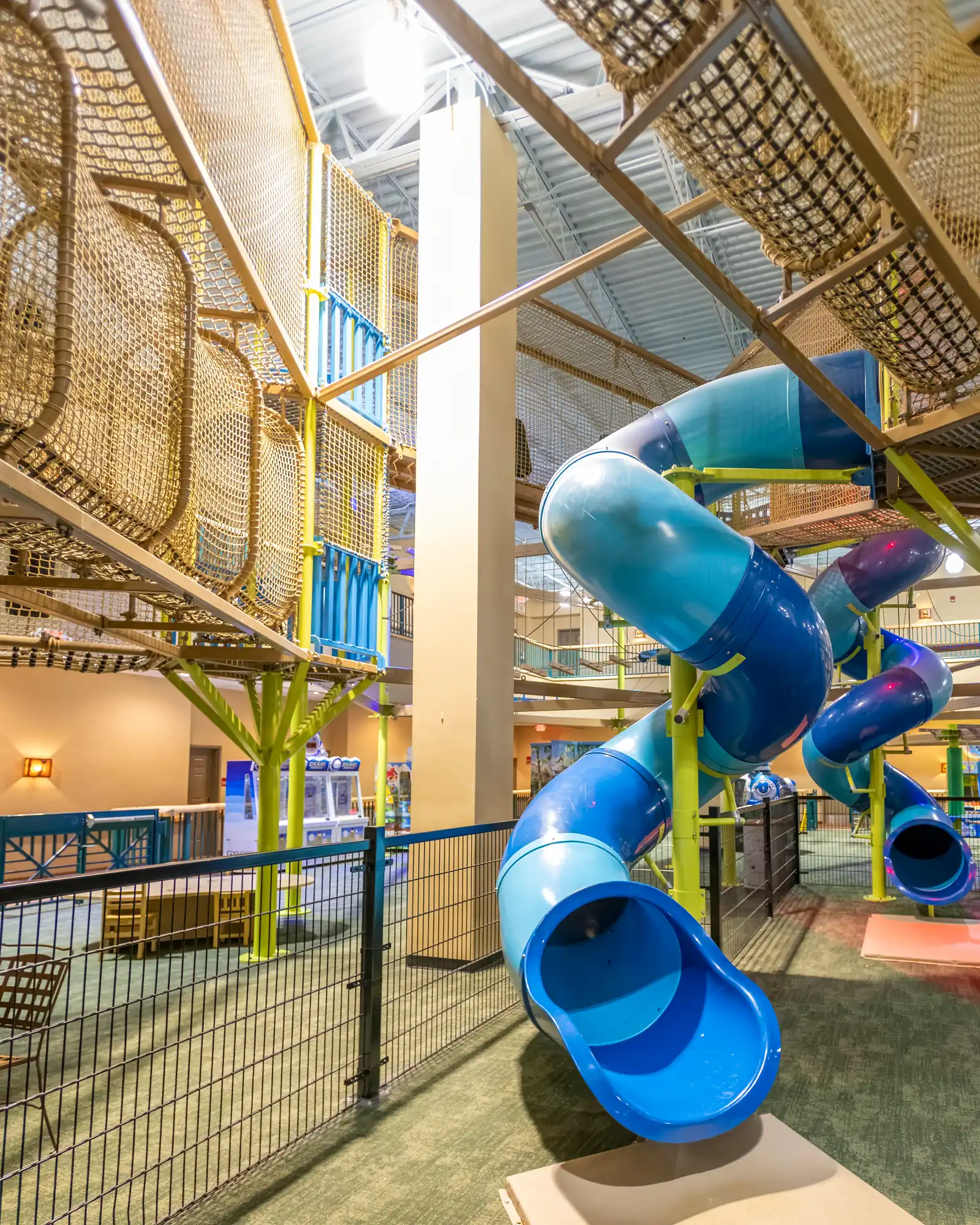 Blue winding tube slide below the adventure park's multilevel netted course.
