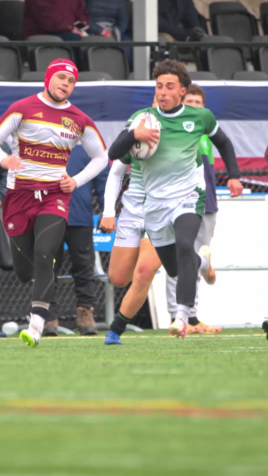 Babson Rugby ball carrier breaking into space with an opposing player running behind him.