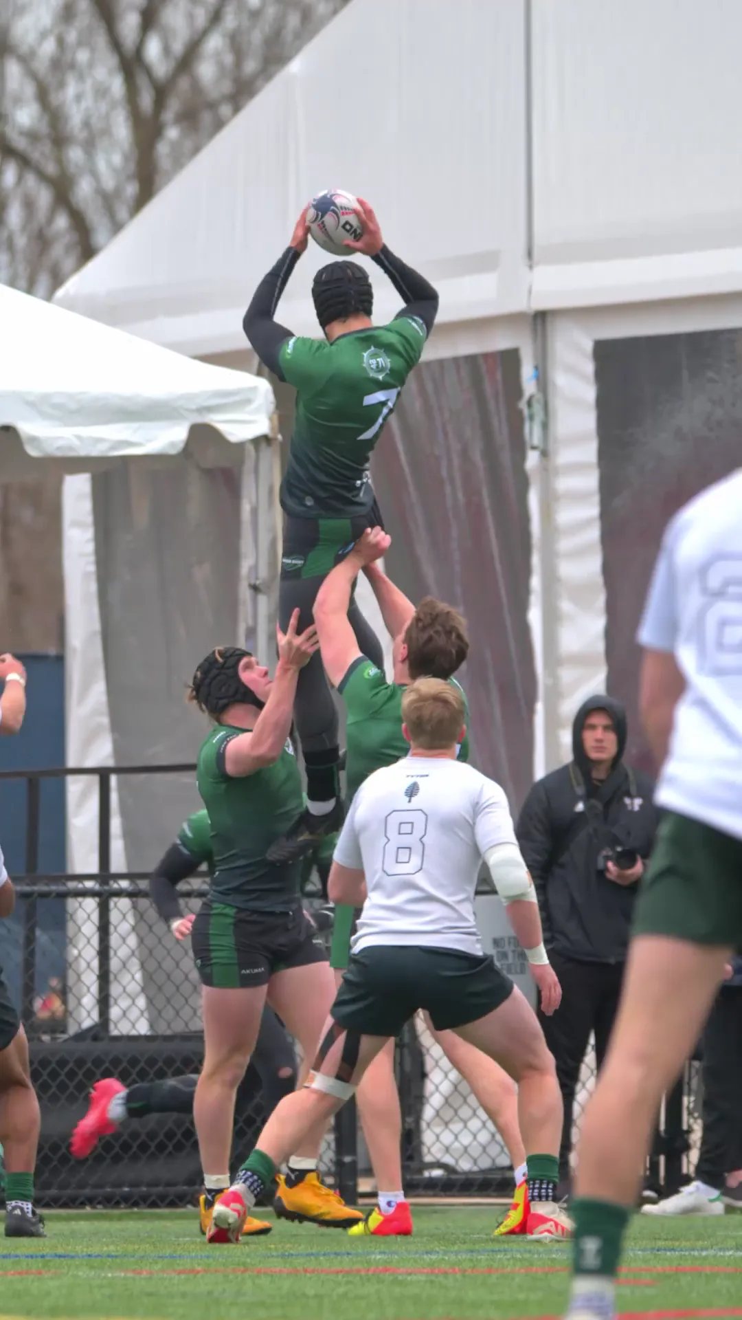 Babson Rugby player claiming the ball in a lineout while teammates lift him.