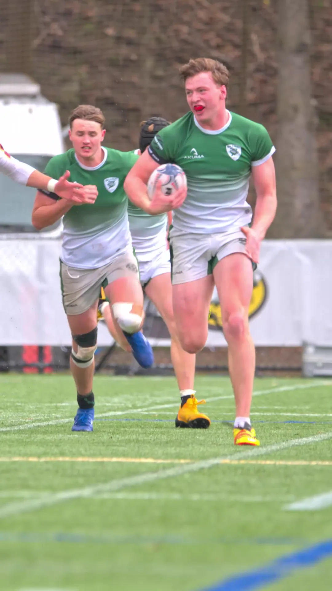 Babson Rugby ball carrier advancing with two teammates running in support.