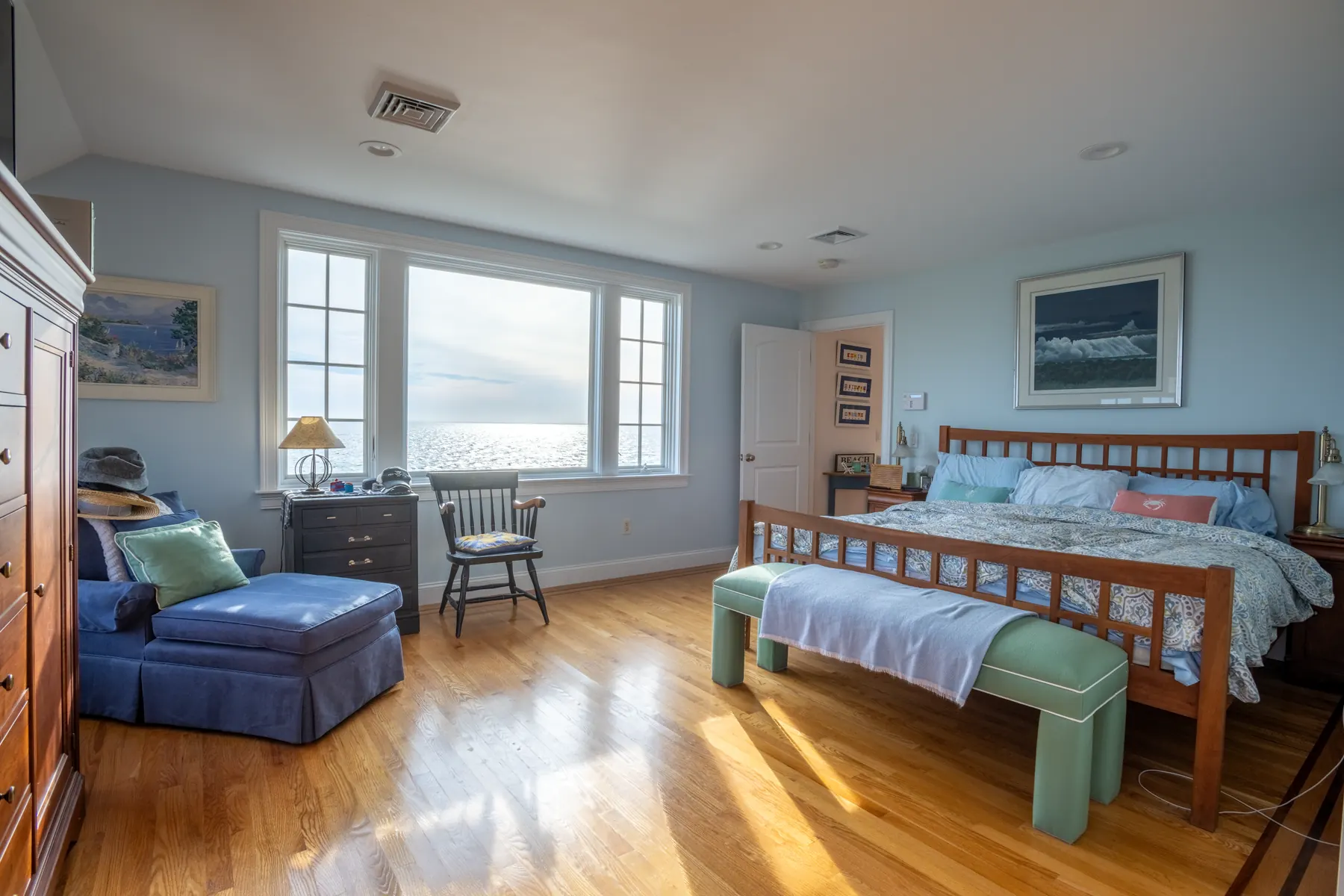 Bedroom with corner windows overlooking dunes and the water.