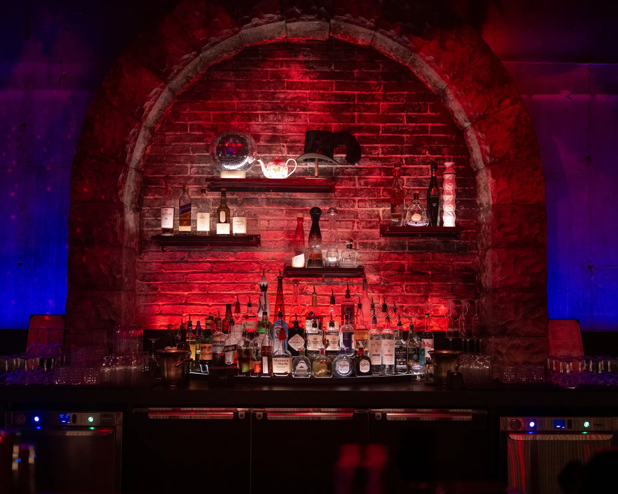Arched brick backbar illuminated in red and blue.