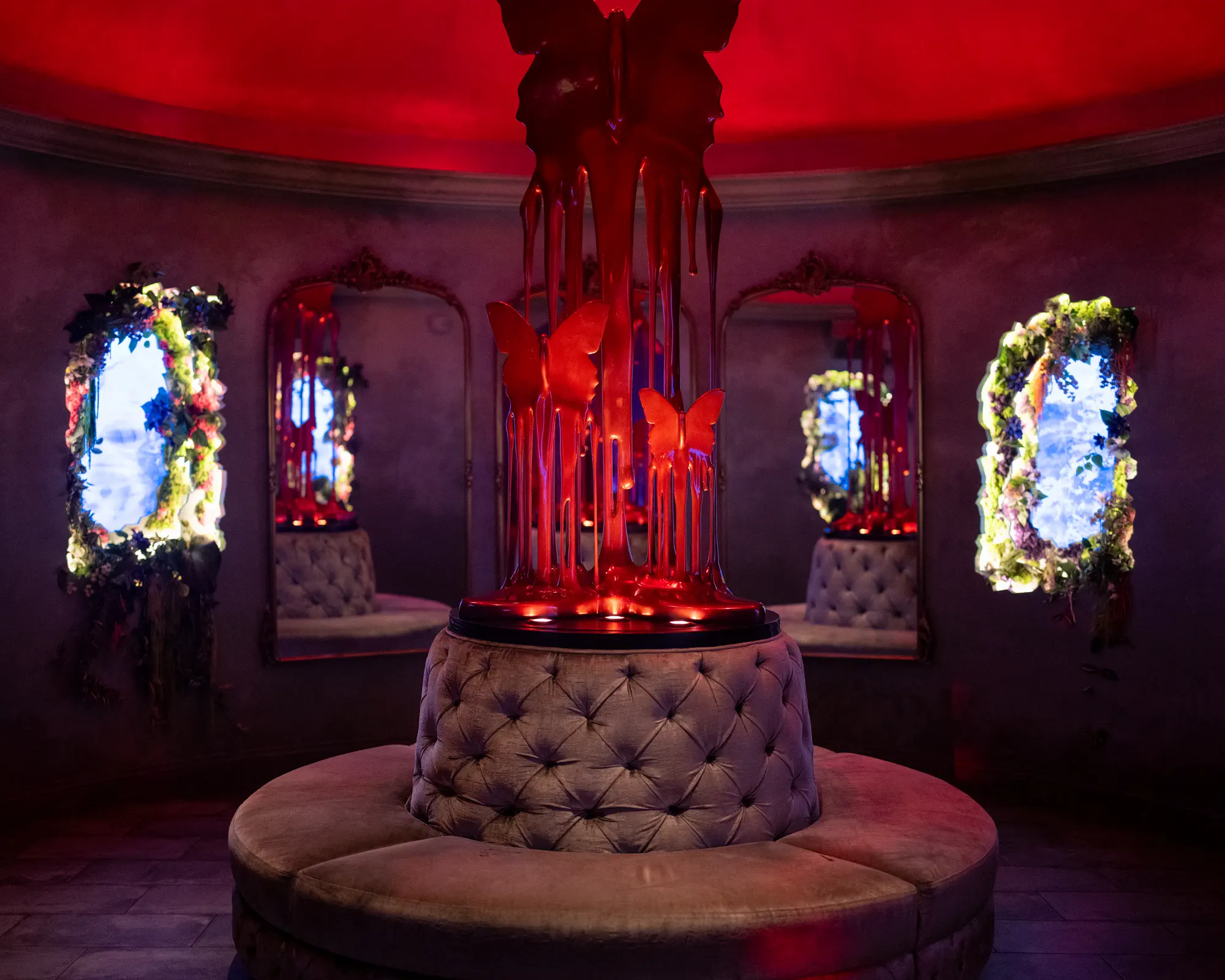 Sculptural nightclub centerpiece surrounded by illuminated mirrors and banquette seating.