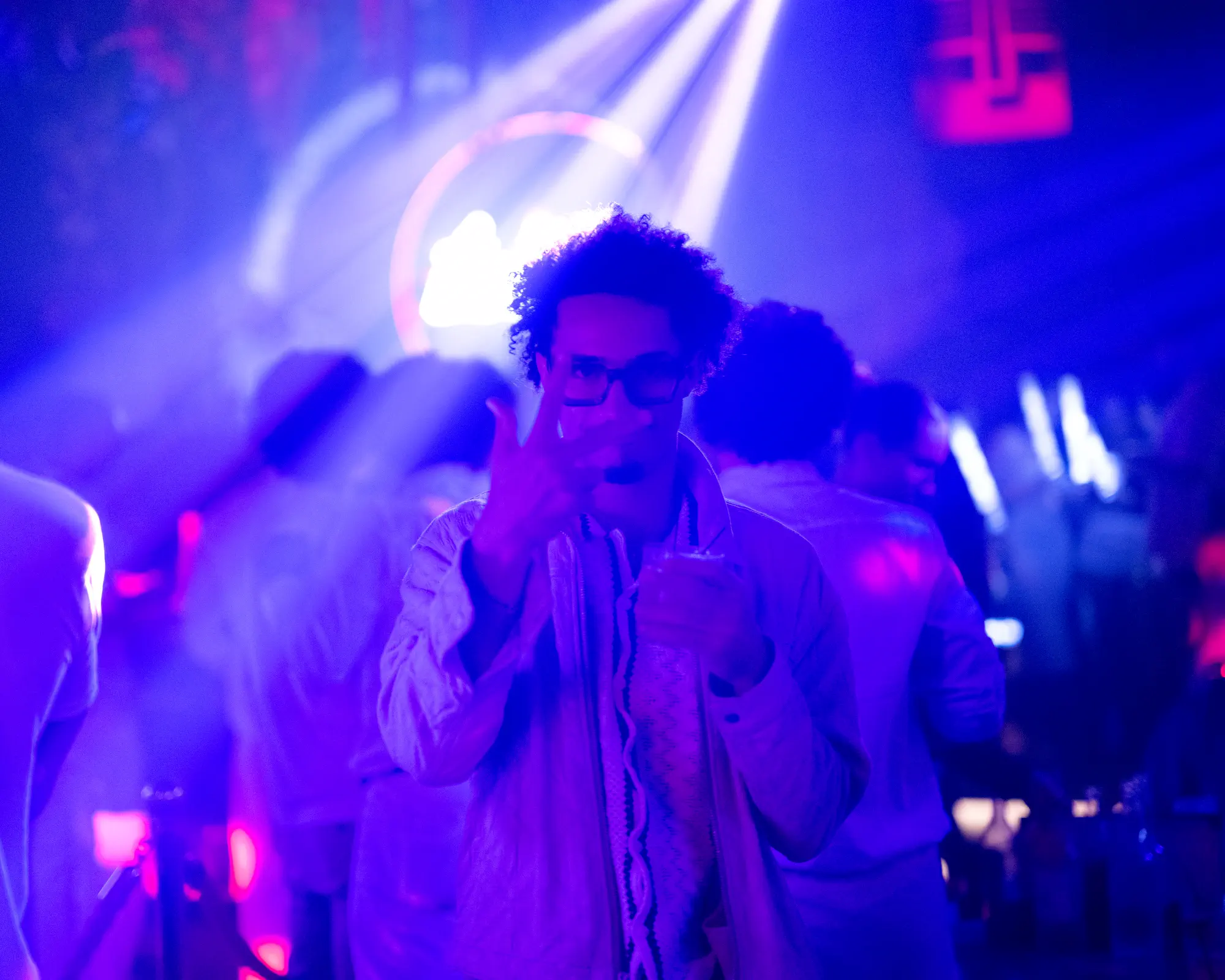 Nightclub guest posing beneath blue and purple lights.