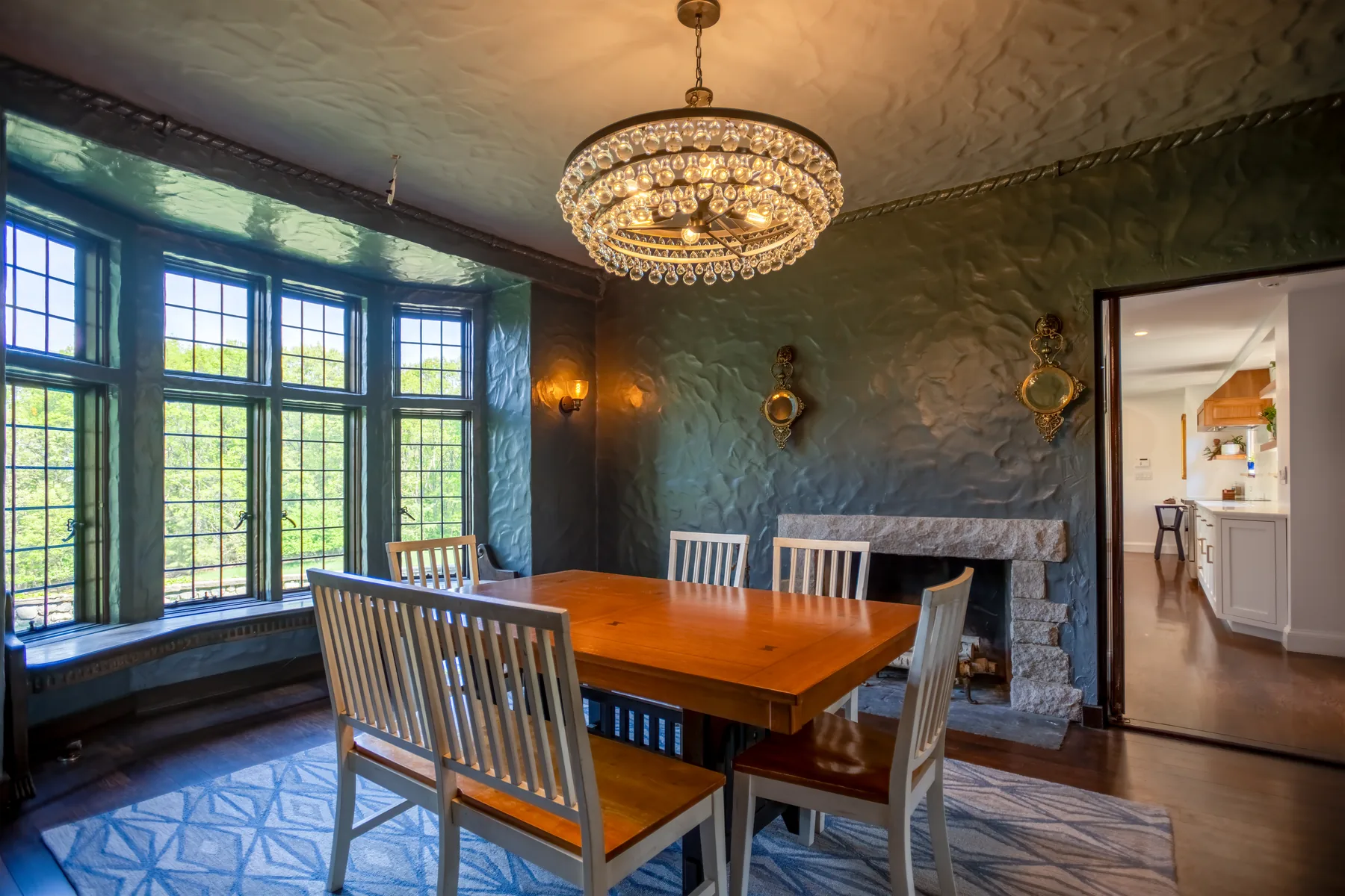 Formal dining room with leaded windows, a stone fireplace, and chandelier.