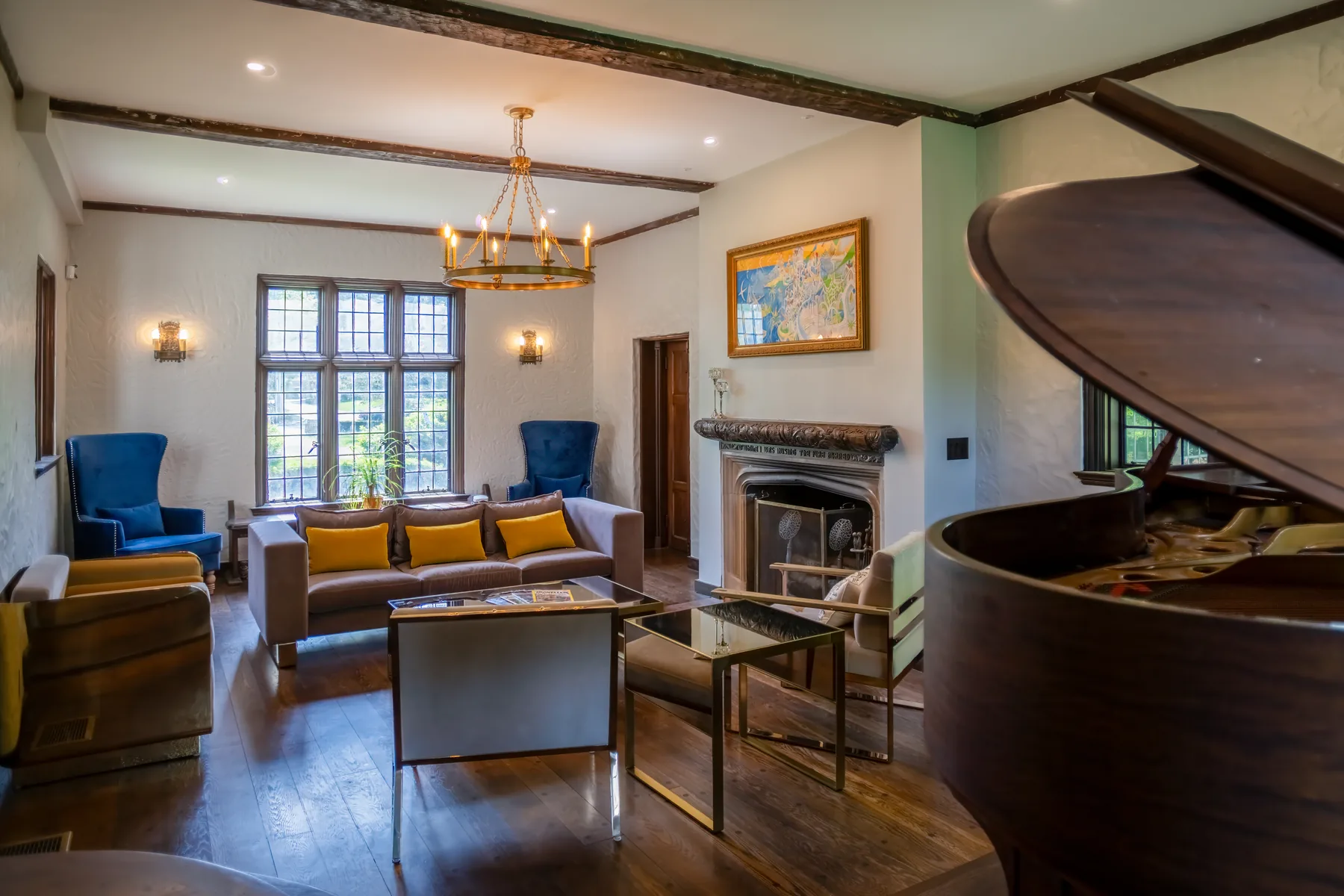 Sunlit family room with a grand piano, fireplace, and exposed ceiling beams.