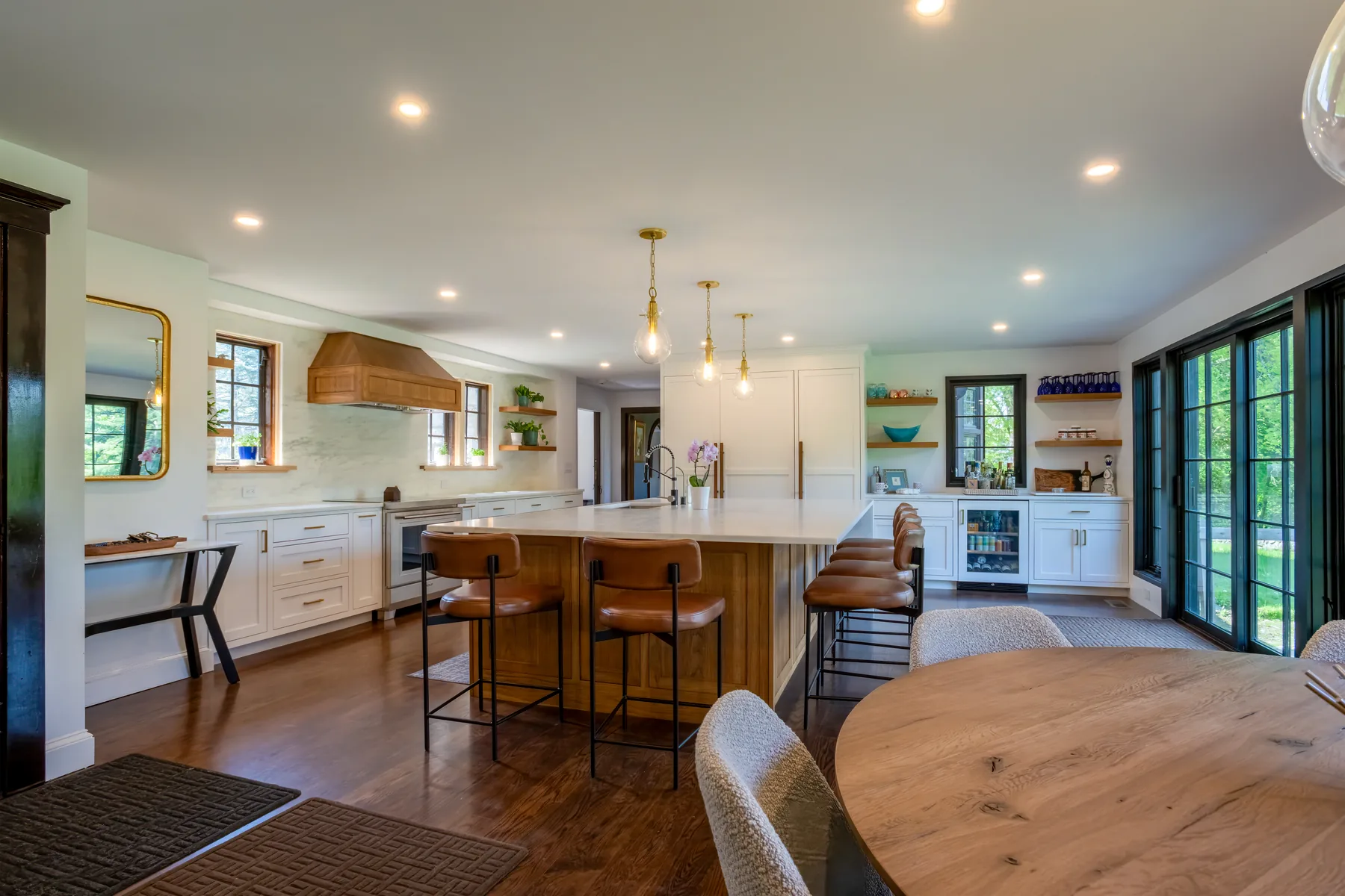 White kitchen with a wood island, breakfast table, and doors opening to the garden.