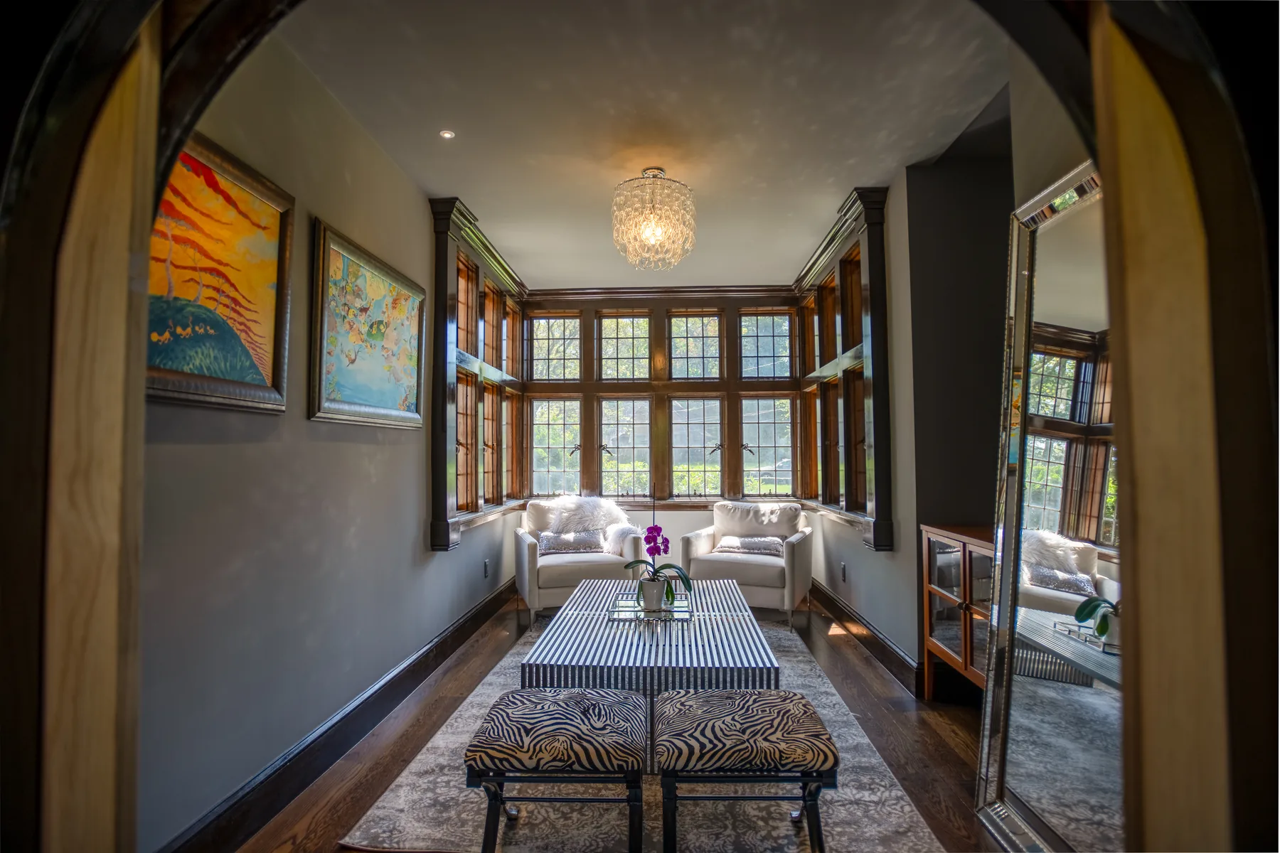 Long sitting room with leaded windows, dark wood trim, and patterned seating.