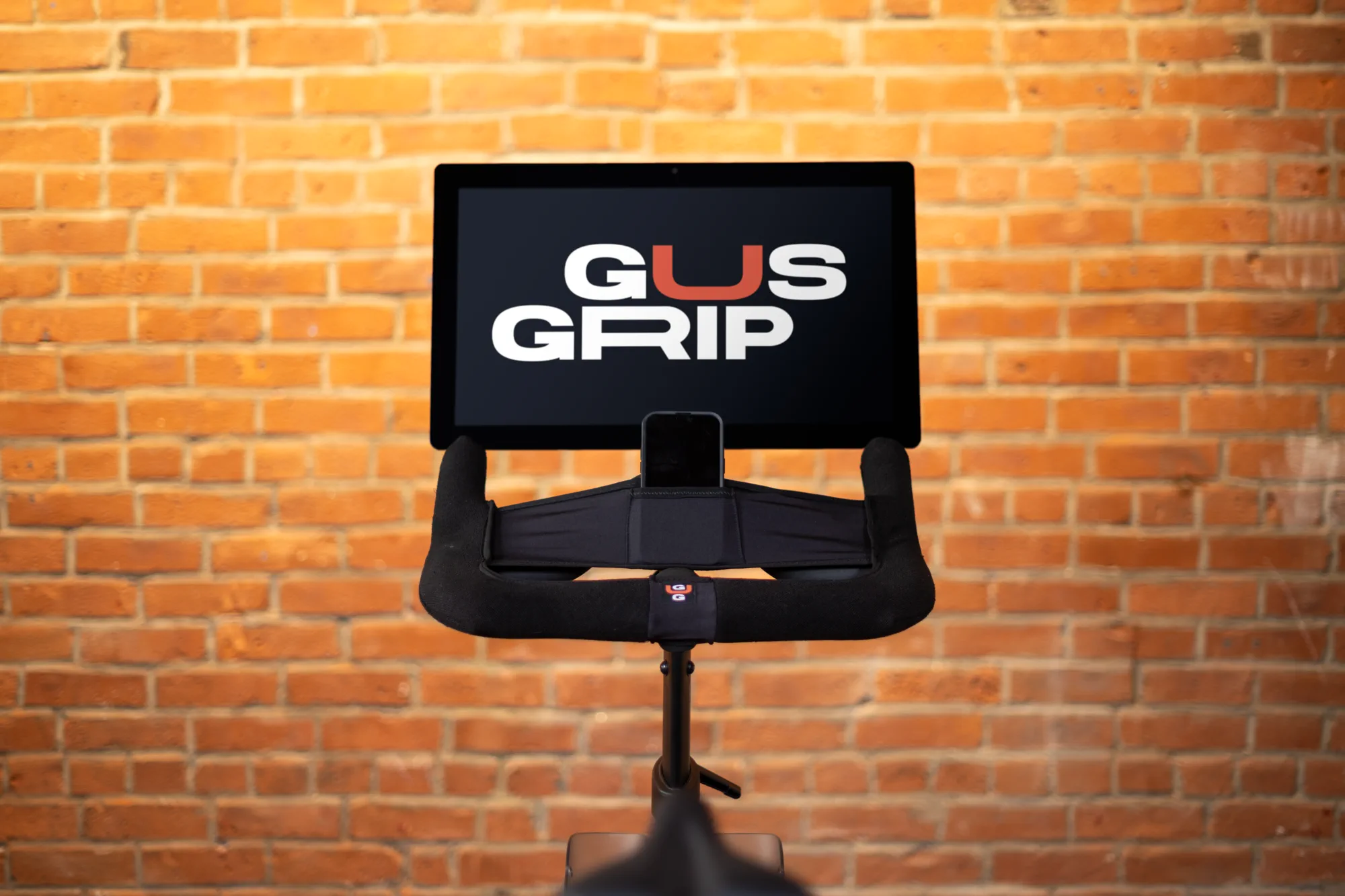 Gus Grips handlebar cover installed on an indoor cycling machine beneath the product logo.
