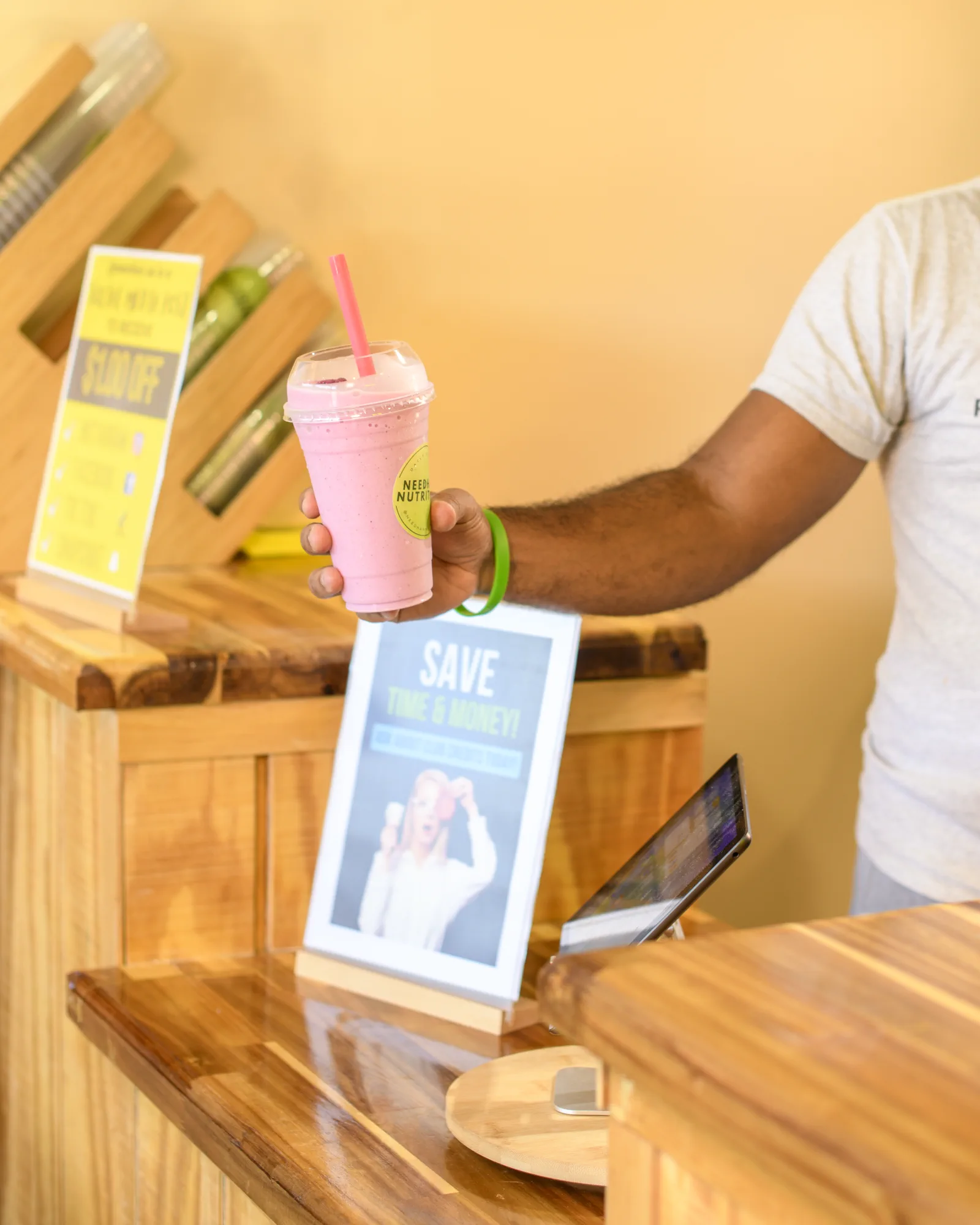 Person holding a pink drink across the Needham Nutrition wood service counter.