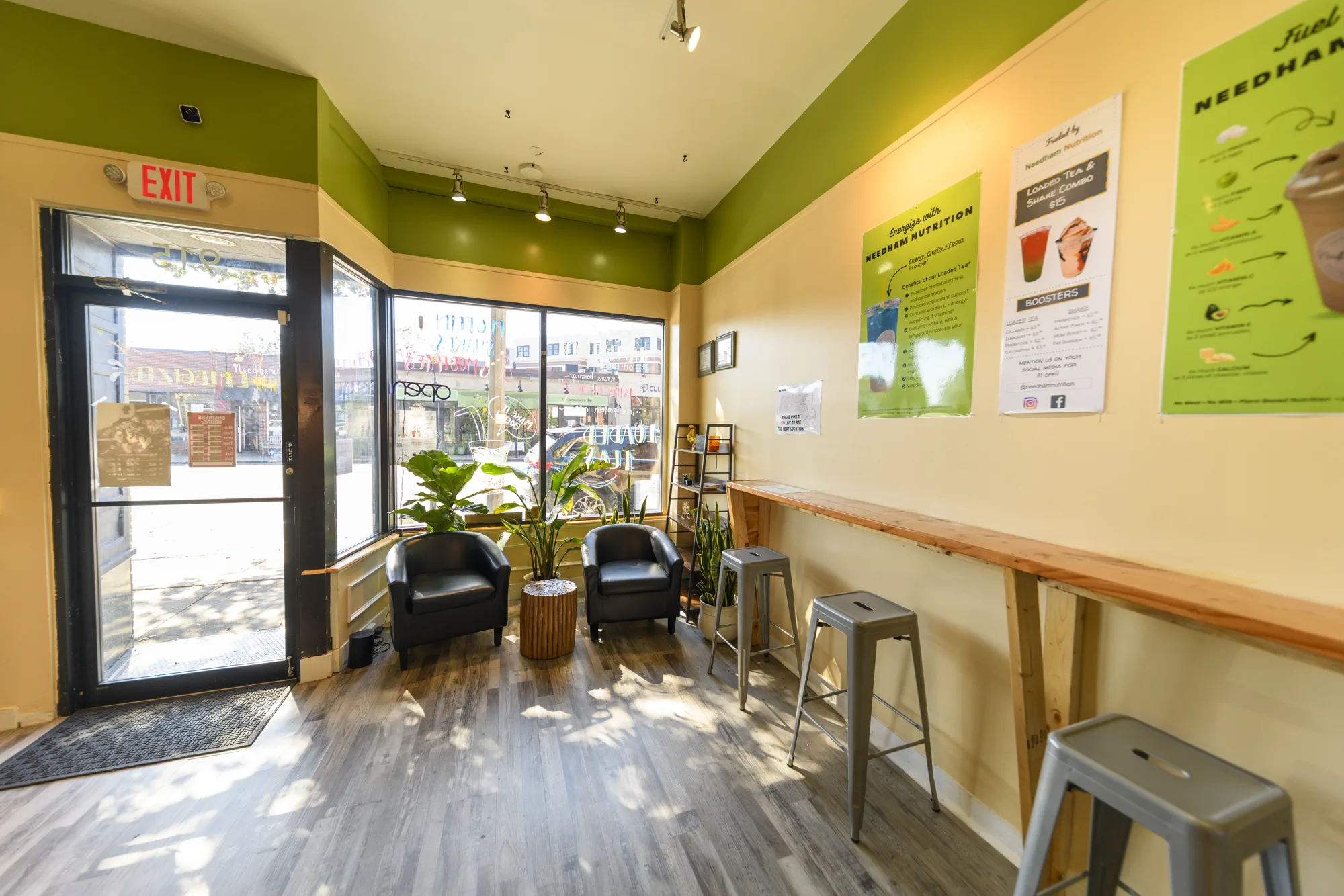 Needham Nutrition storefront interior with green accents, window seating, and a wood counter.
