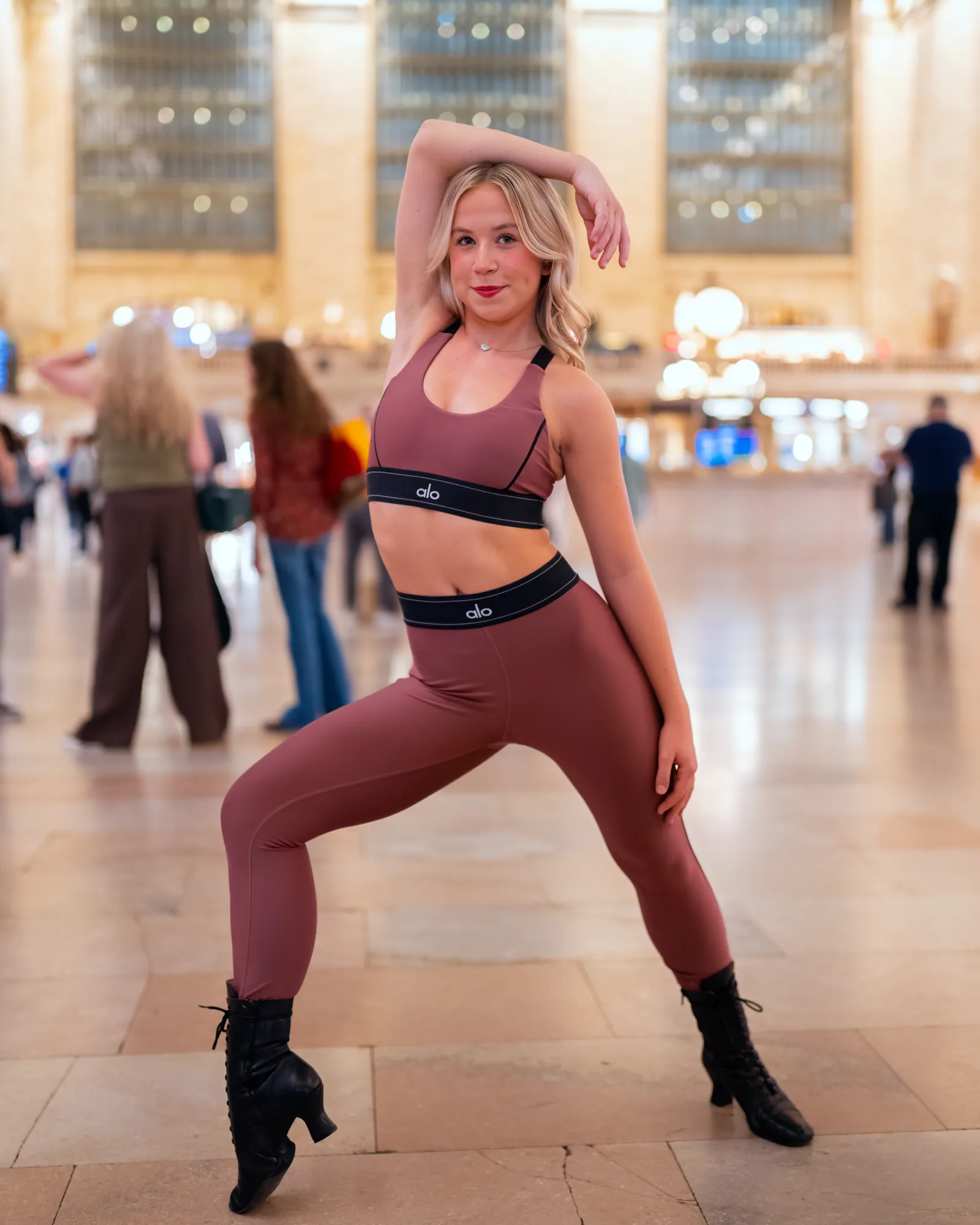 Dancer holding a wide grounded pose on a New York City train terminal concourse.