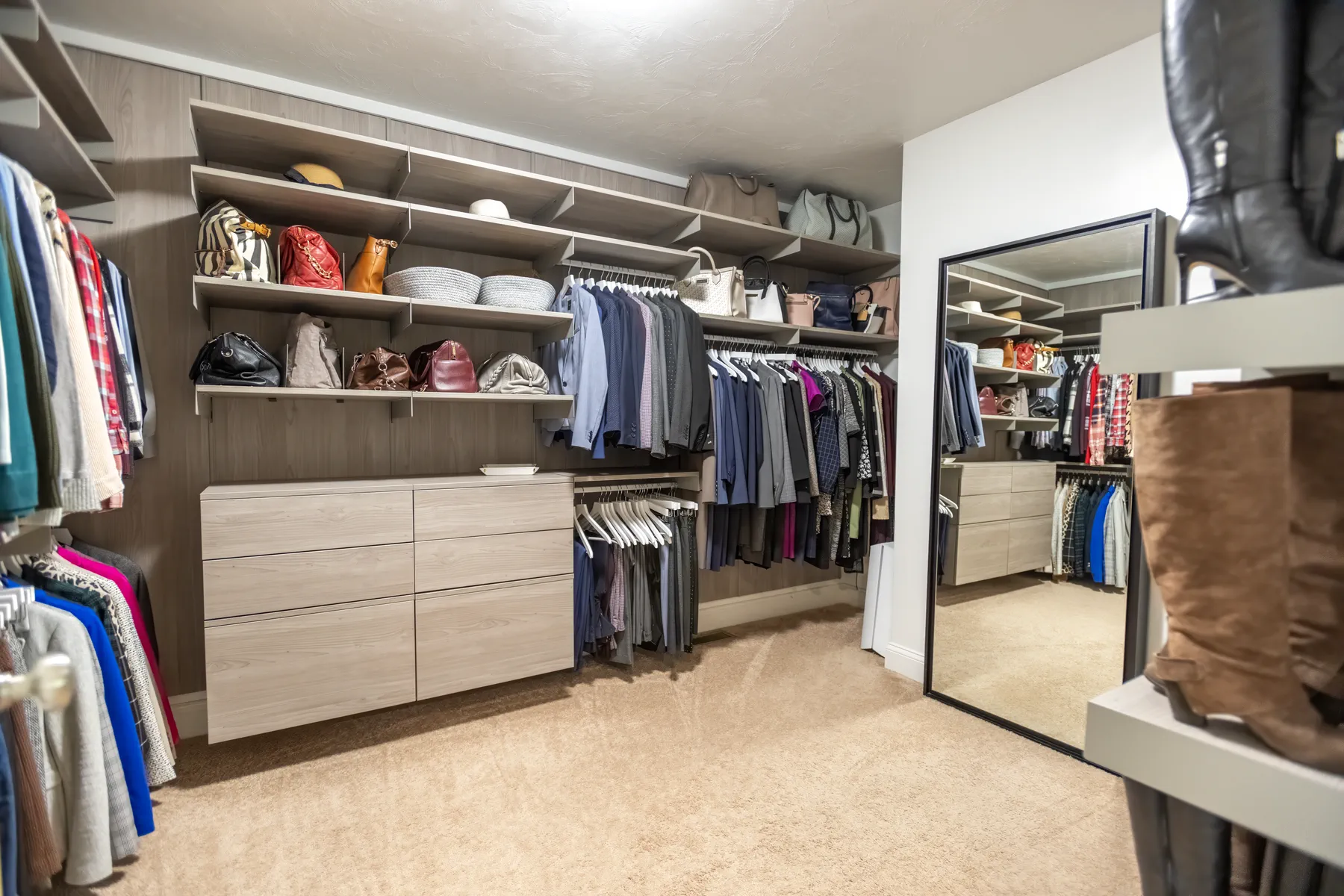 Walk-in closet with custom shelving, drawers, hanging storage, and a full-length mirror.