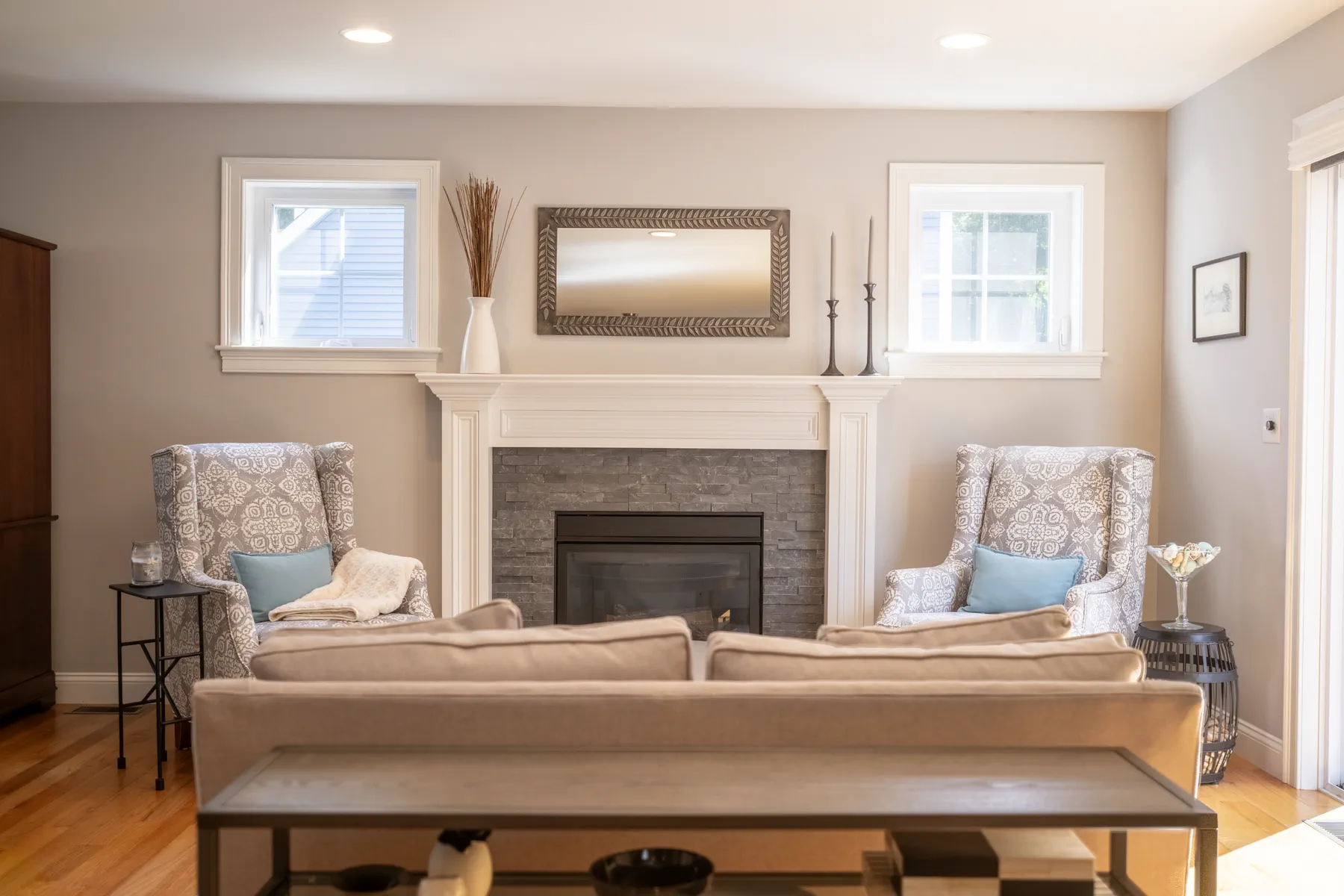 Family room arranged around a white fireplace with two patterned armchairs.