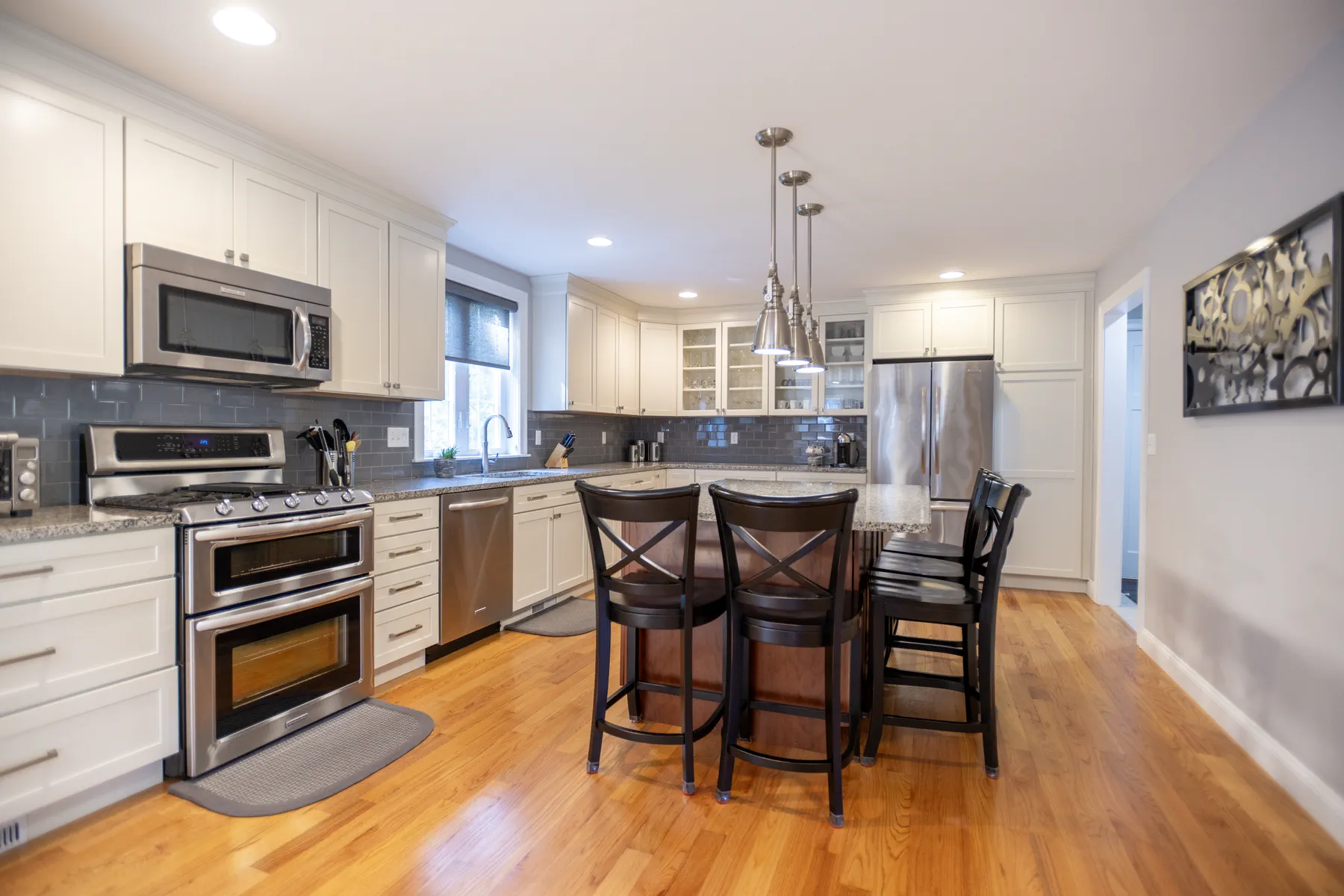 White kitchen with stainless appliances, stone counters, and a peninsula with bar seating.