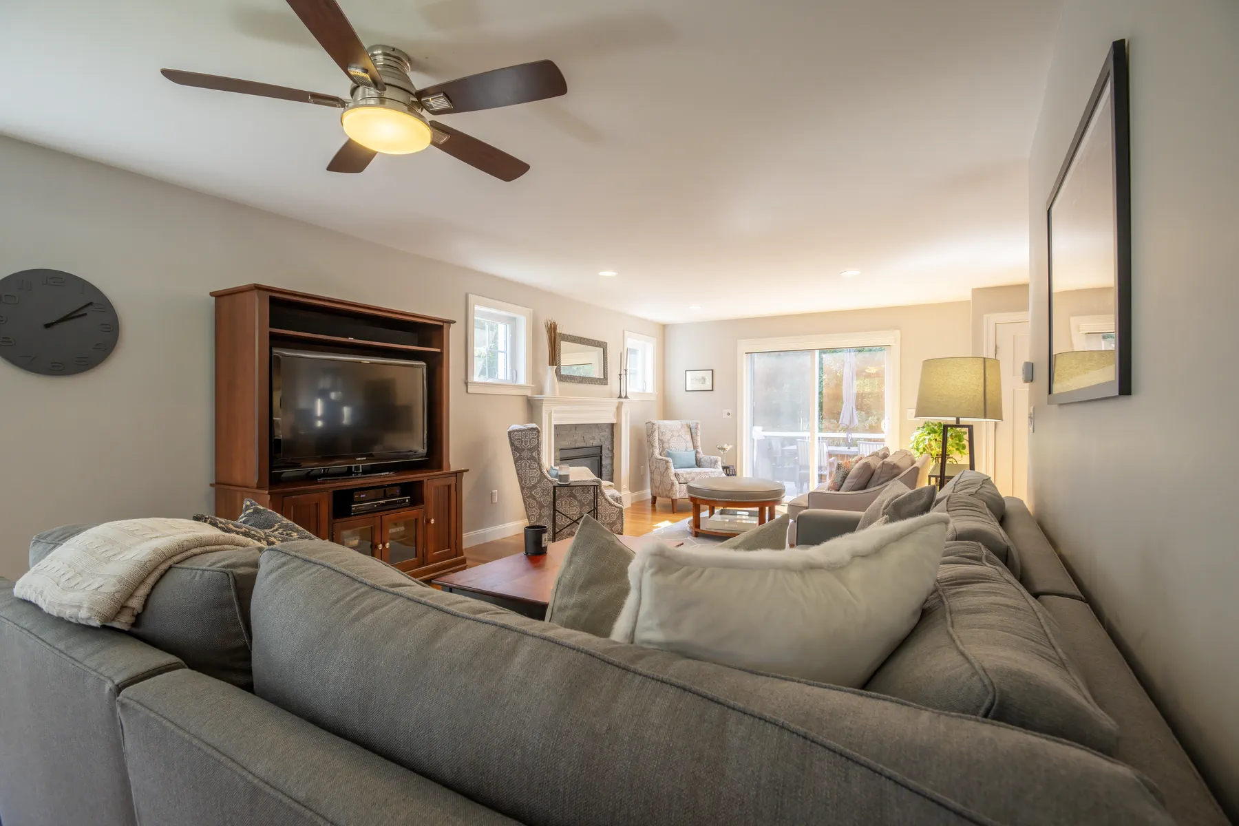 Long living room with a sectional sofa, fireplace, and glass doors opening to the yard.