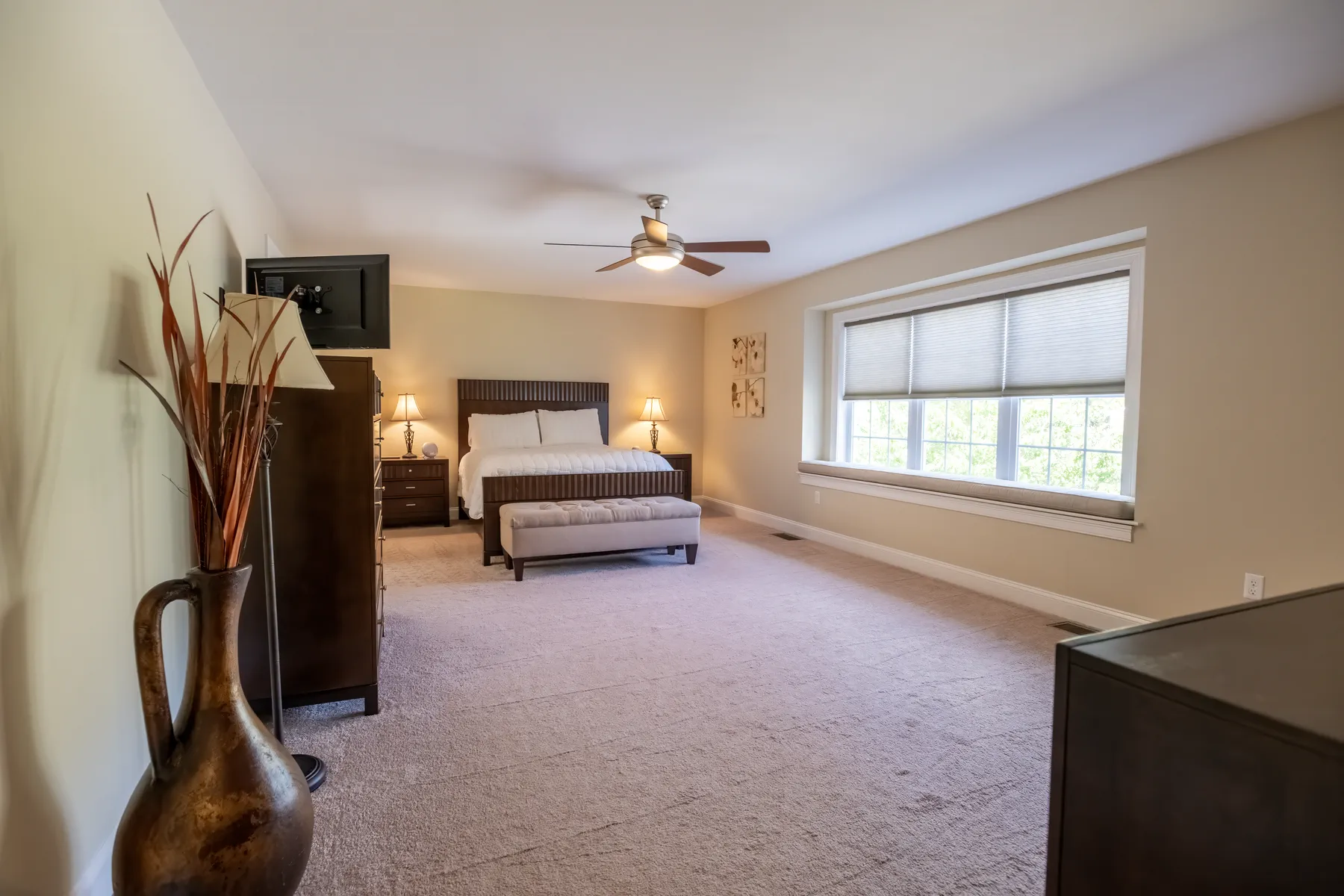 Spacious primary bedroom with neutral carpeting and windows along two walls.