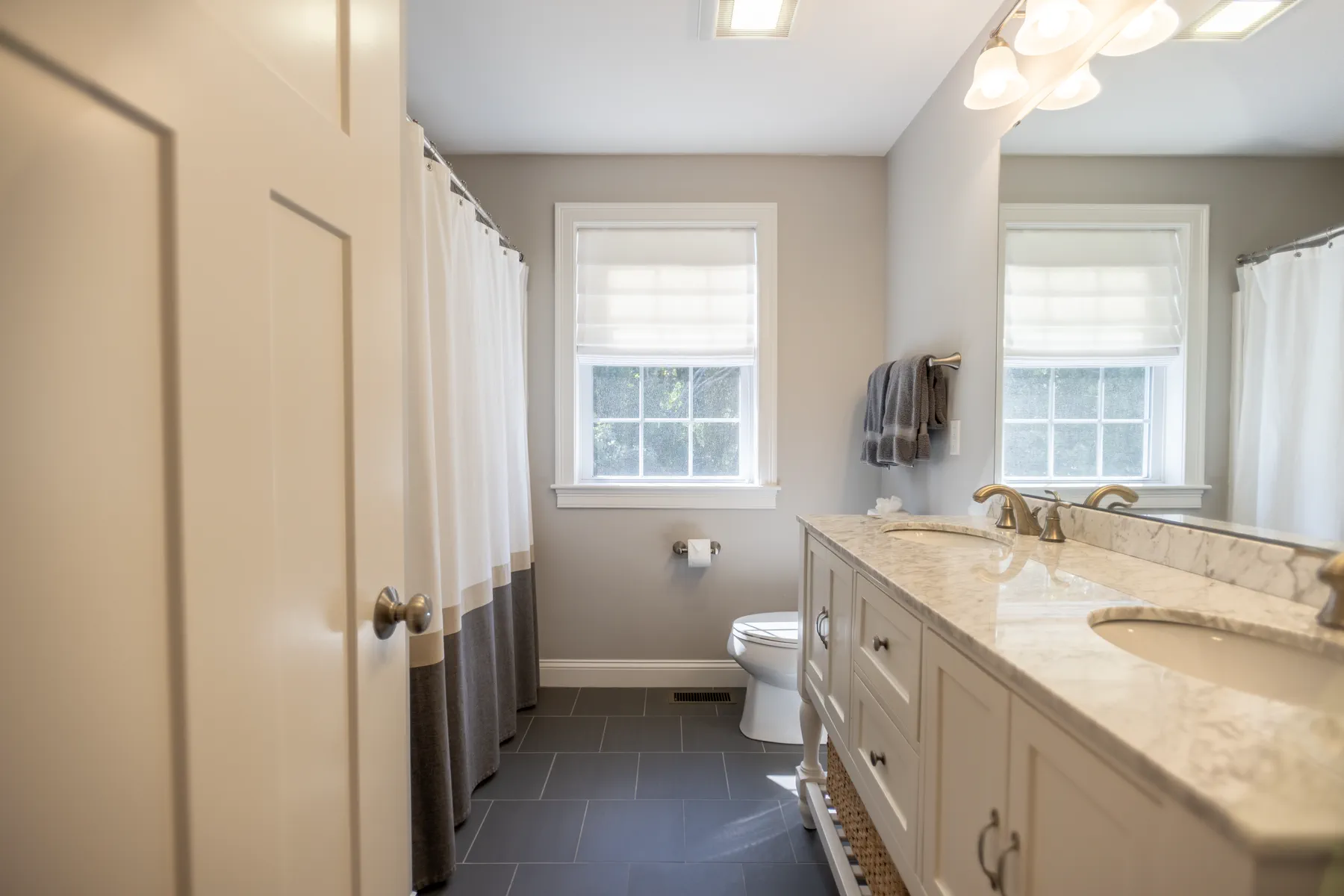 Secondary bathroom with a double vanity, blue-gray walls, and a tub shower.