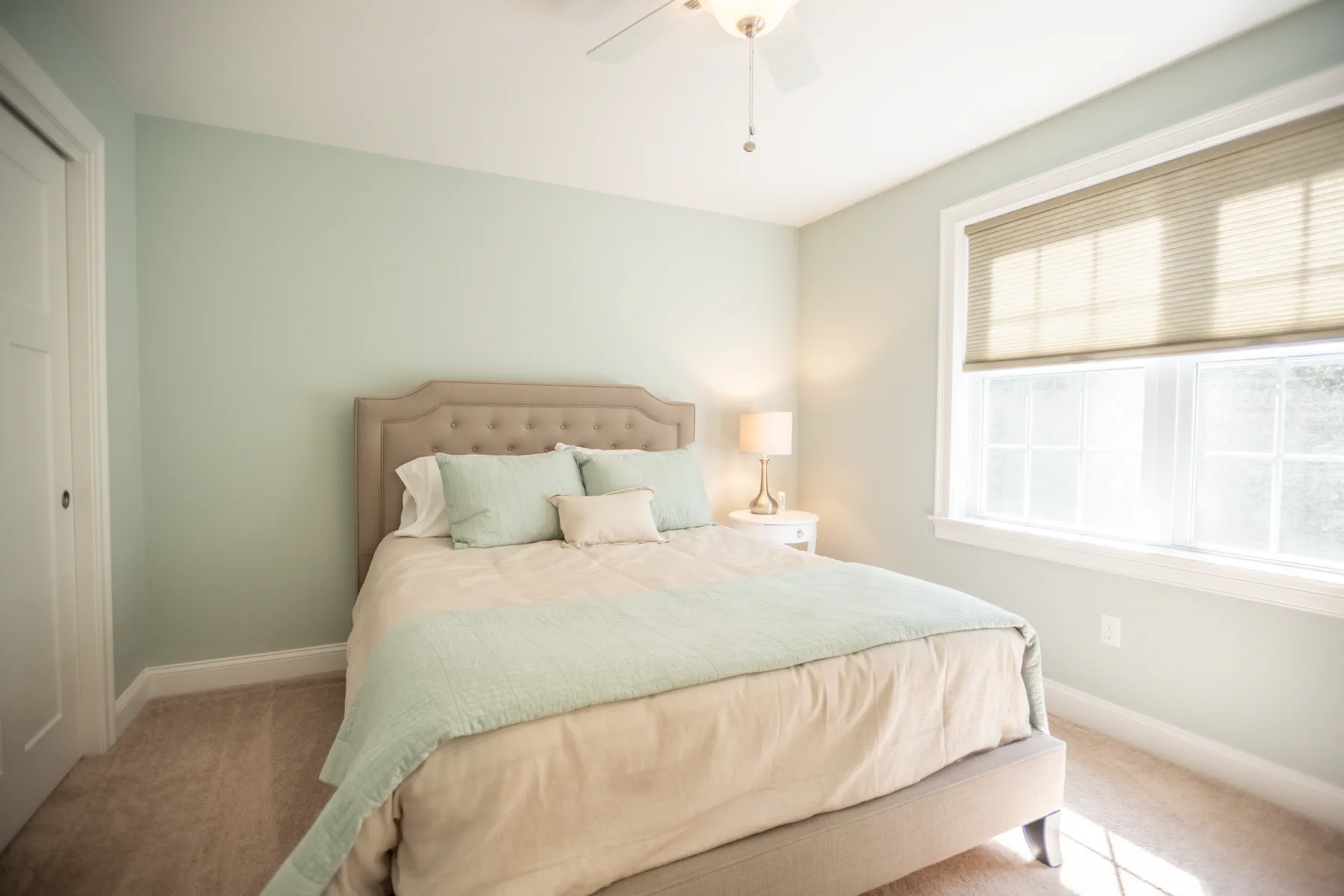 Secondary bedroom with pale blue walls, a padded bed, and two sunlit windows.