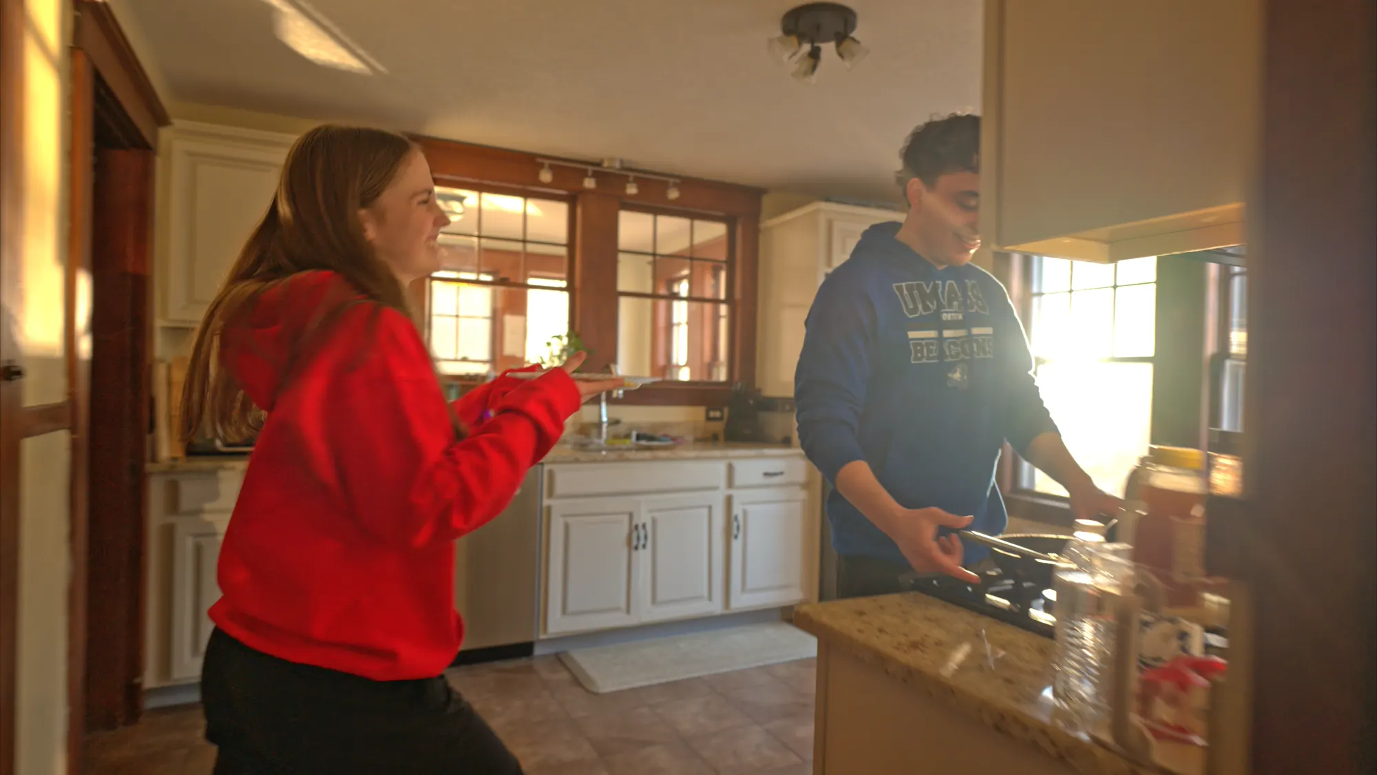 Two housemates preparing breakfast together in a shared kitchen.