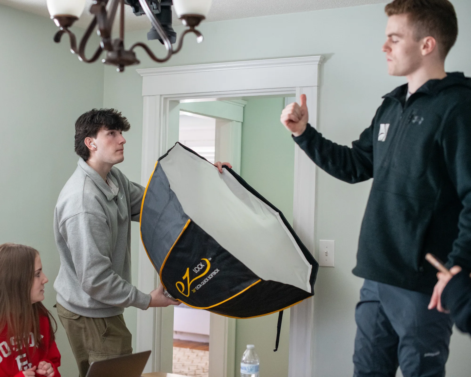 Two crew members positioning a softbox during the Scholar Suites production.