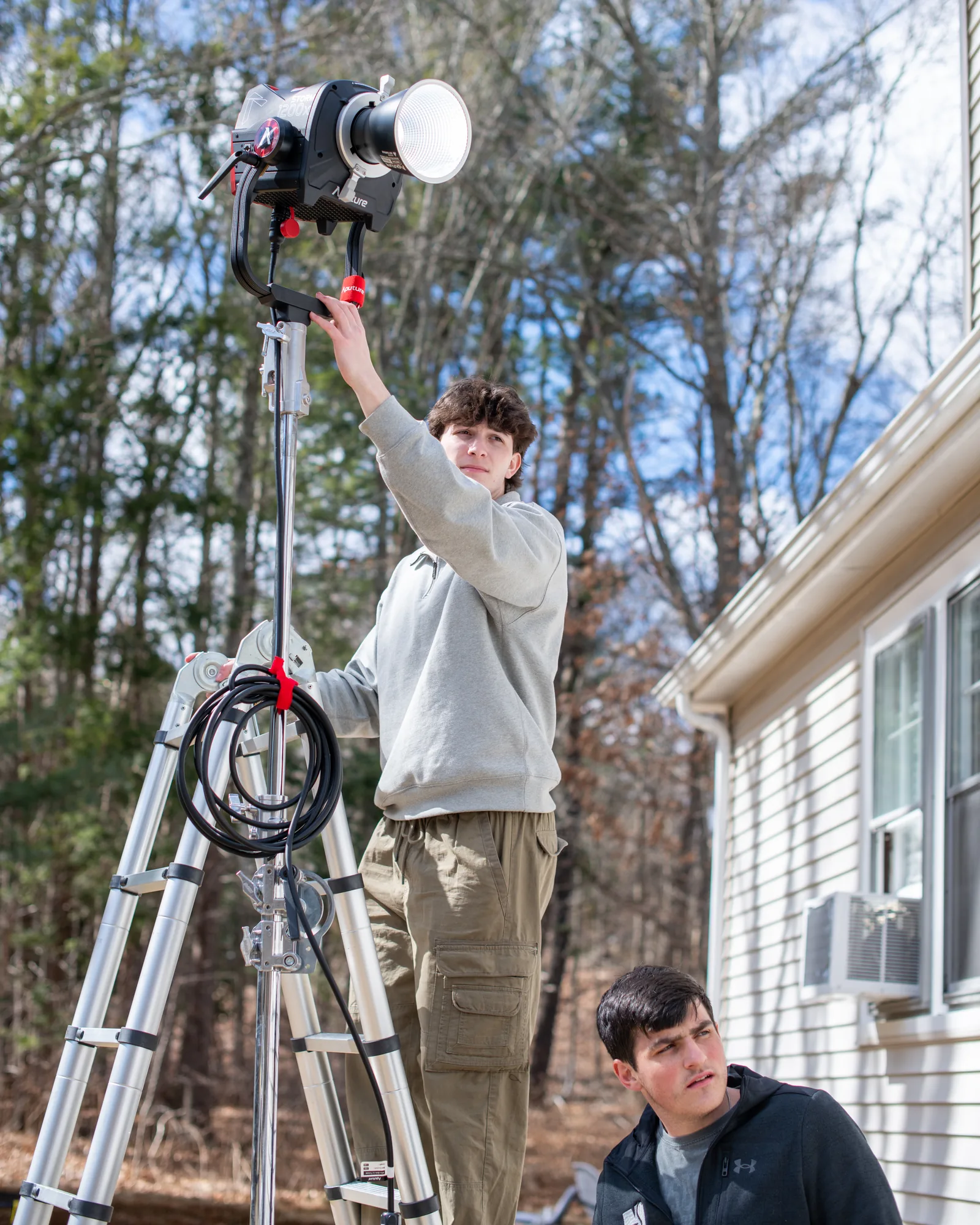 Two crew members setting a tall exterior light for the Scholar Suites production.