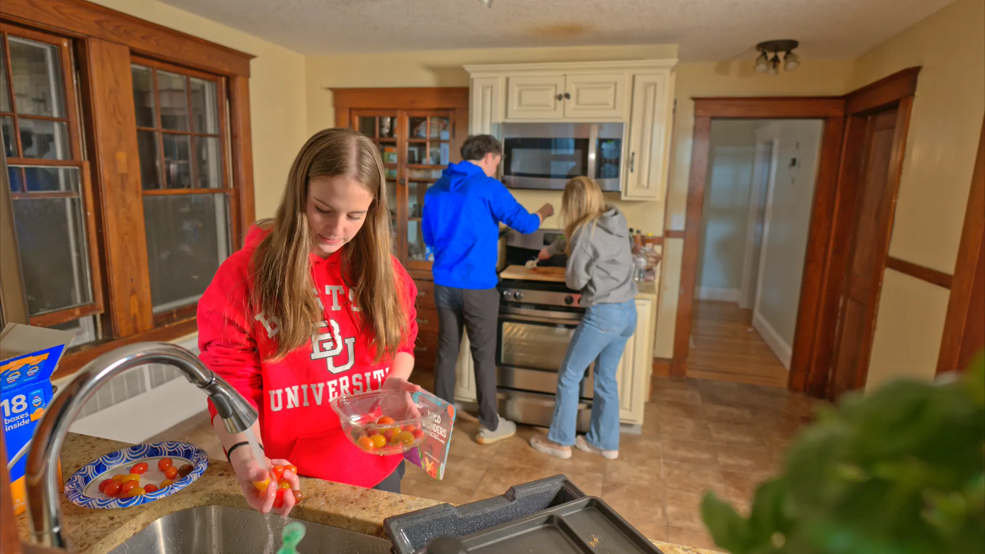 Three housemates cooking dinner in a shared kitchen.