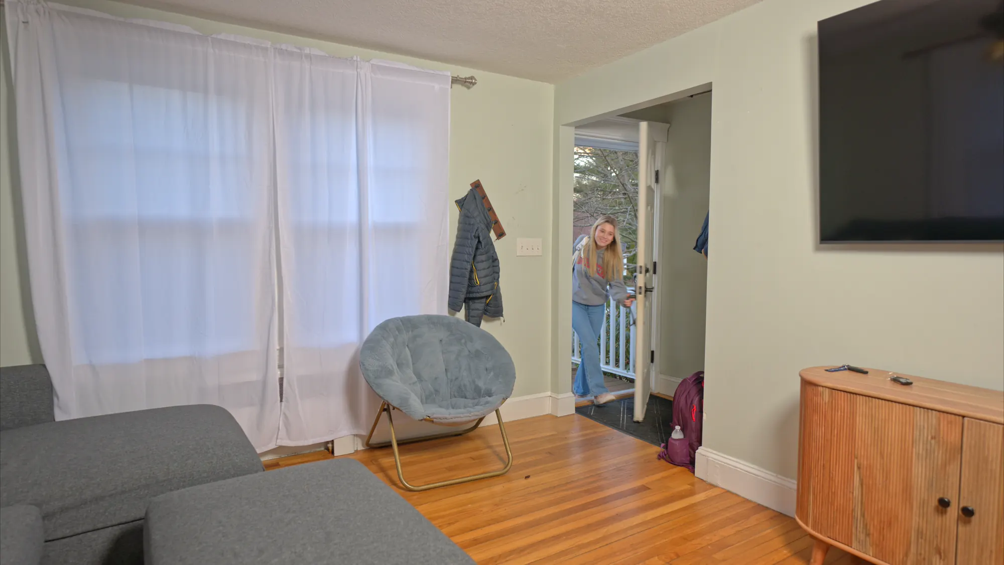 Woman stepping into a furnished Boston apartment living room.