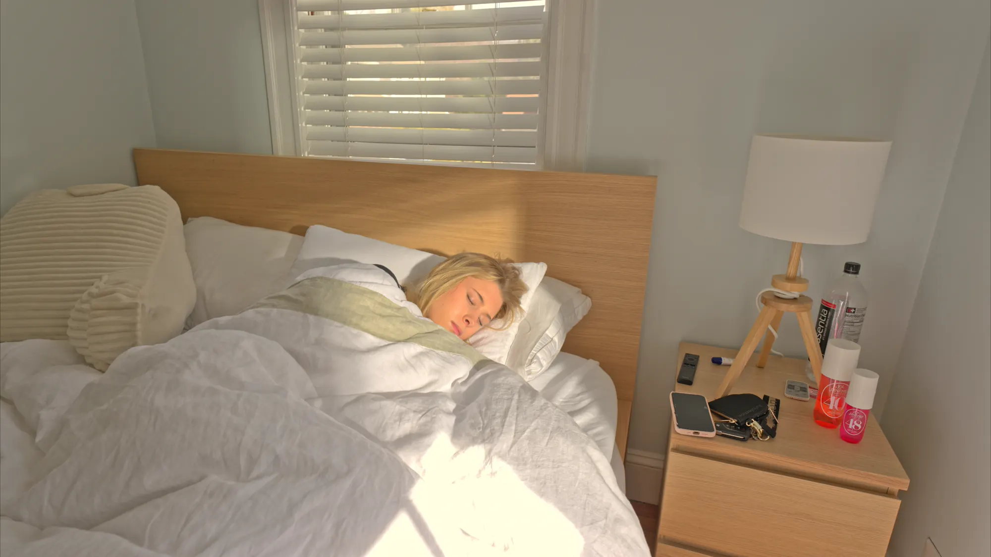 Woman waking in a sunlit bedroom.