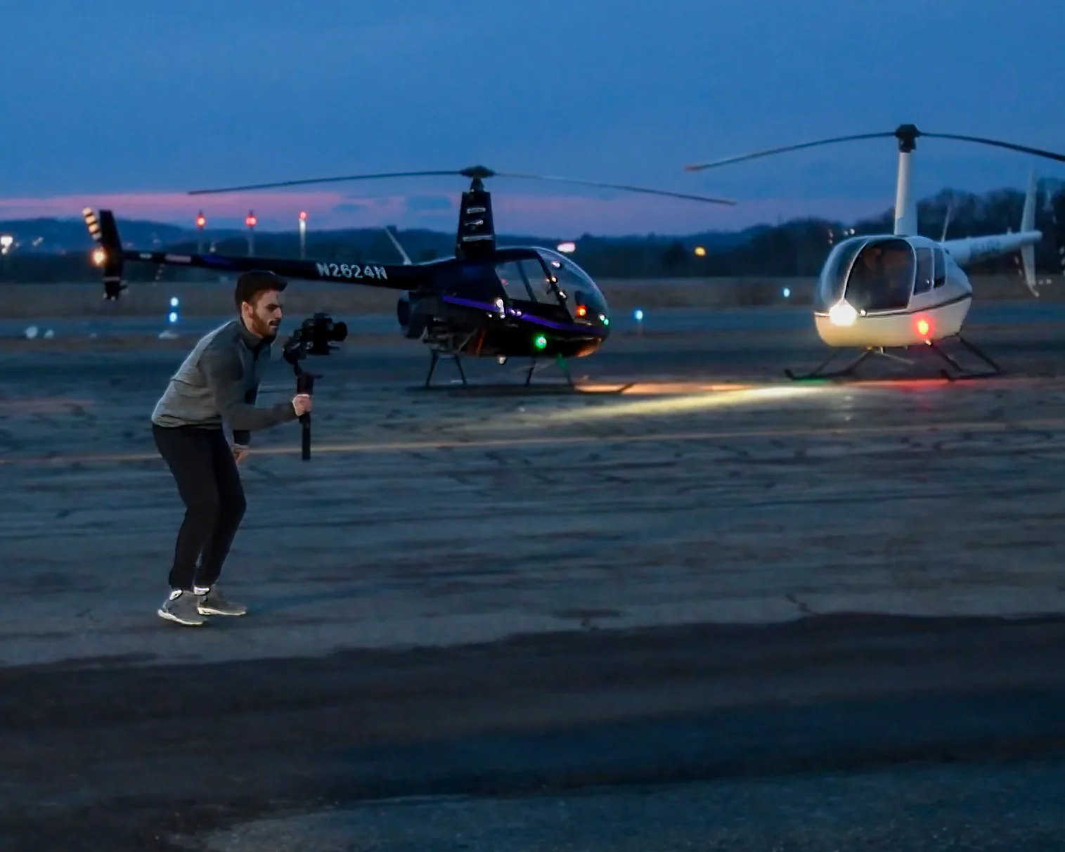 Kyle Soule filming on the airstrip in front of two helicopters during the TAKKRA production.