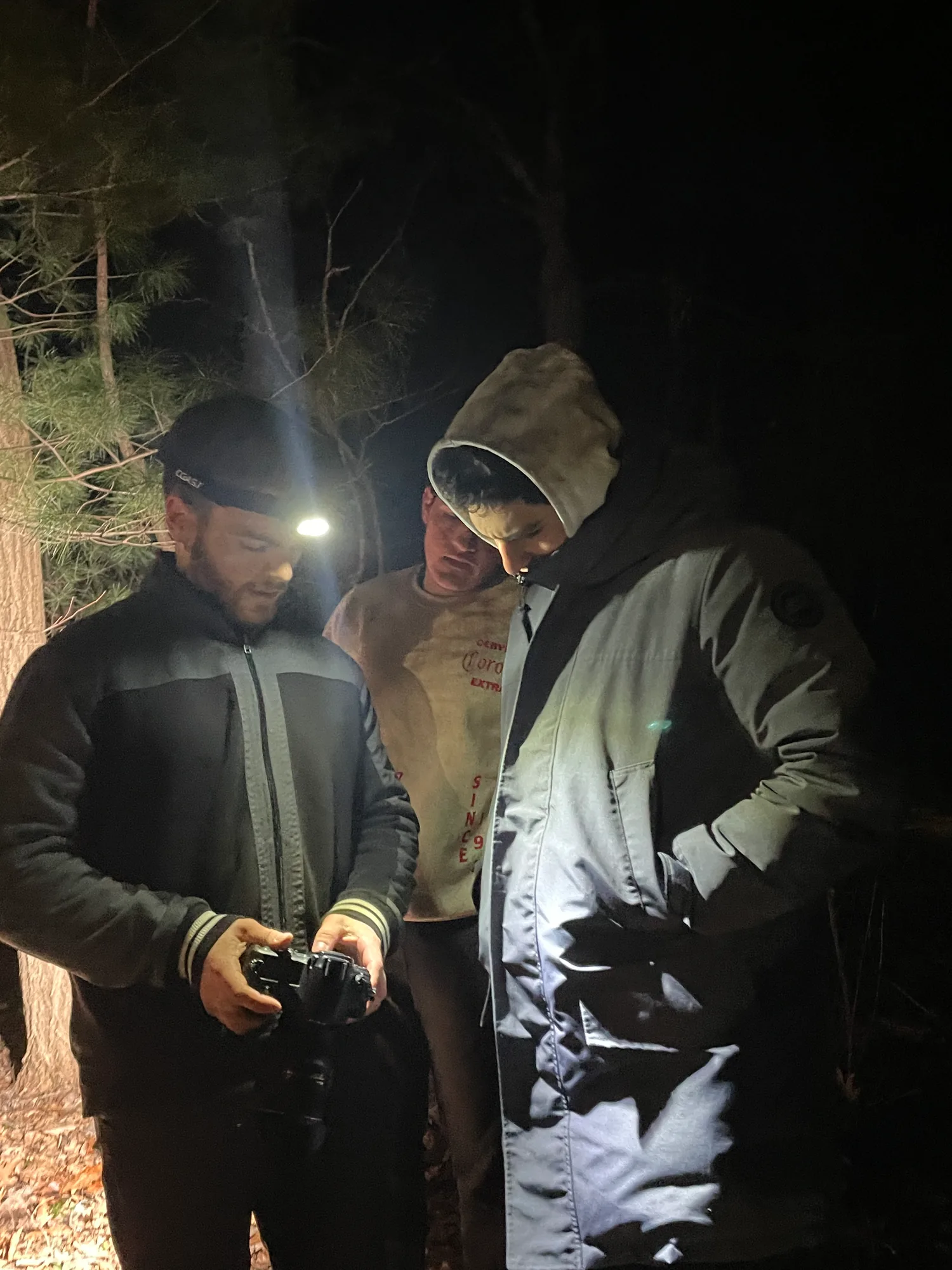 Three crew members reviewing a camera in the woods during the TAKKRA production.