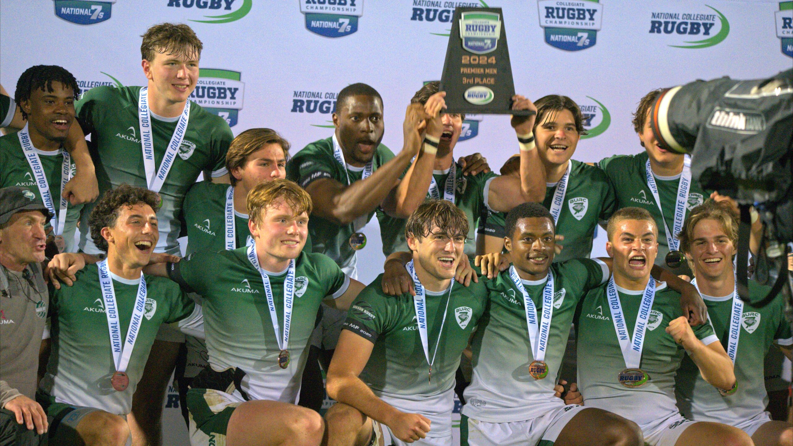 a group of men in green uniforms holding a trophy